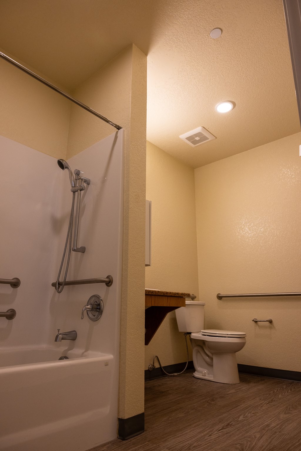 A white bathtub with a shower head and a white toilet in a bathroom.