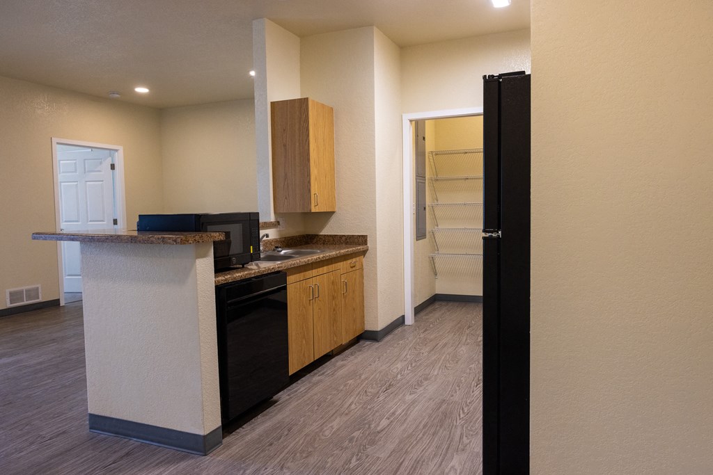 A kitchen with a black dishwasher and wooden cabinets.