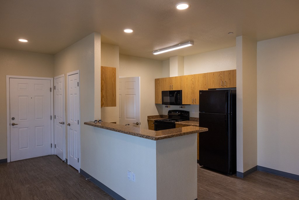 A kitchen area with a black refrigerator and white cabinets.