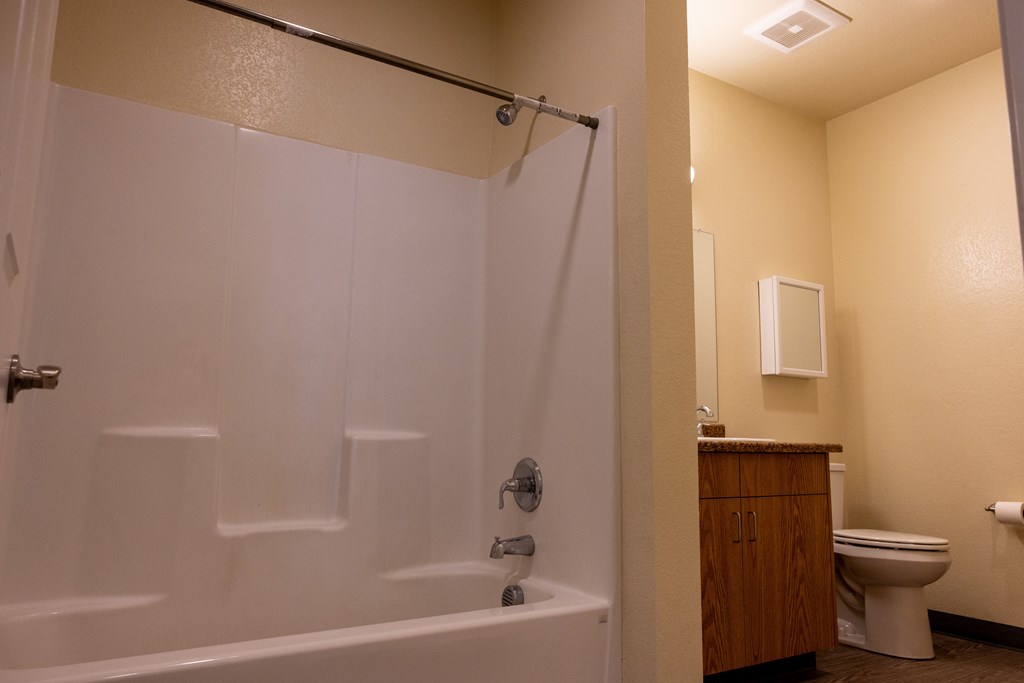 A white bathtub with a shower head and a toilet in a bathroom.