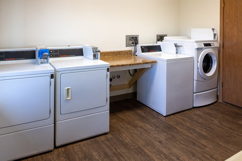 a laundry room with four washers and dryers and a counter with two machines