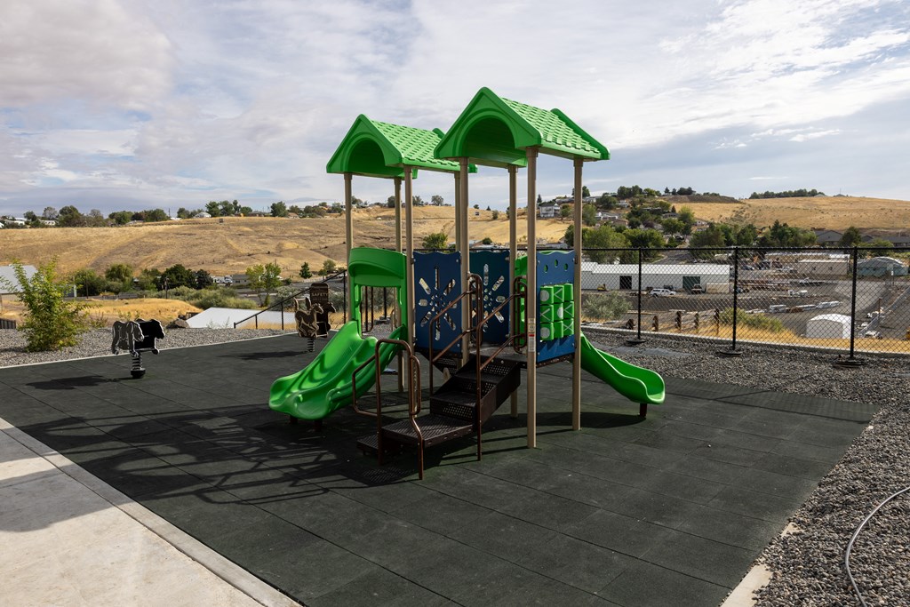 A playground with a green slide and a green roofed structure.