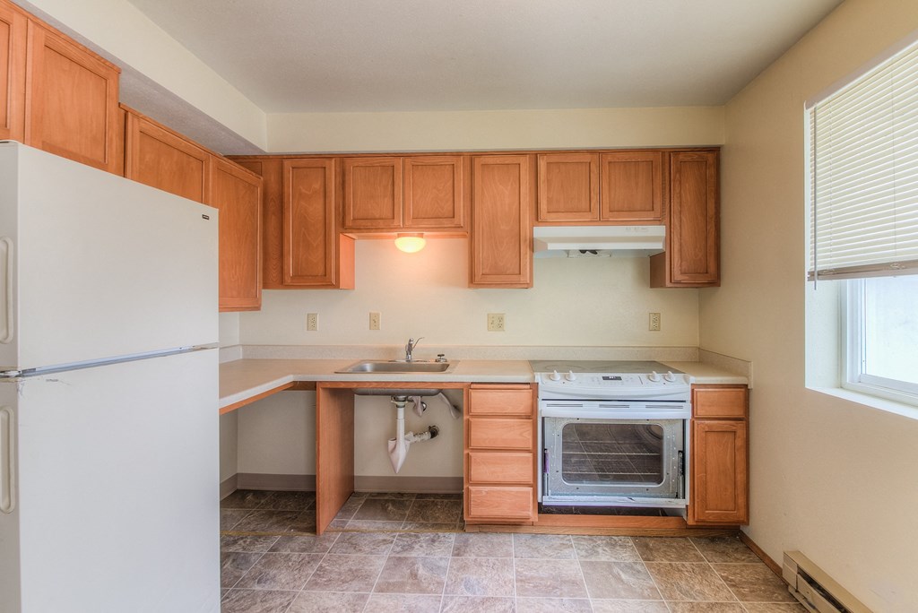 A kitchen with wooden cabinets and a white refrigerator.