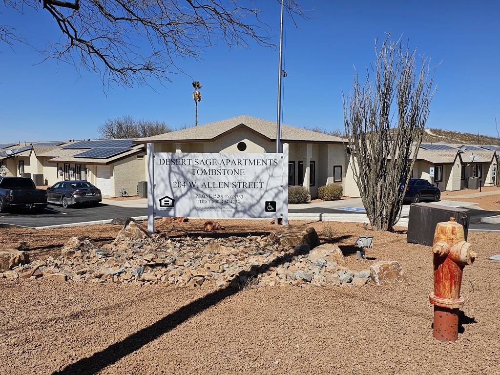 A sign for Desert Sage Apartments in Tombstone stands in front of a building.