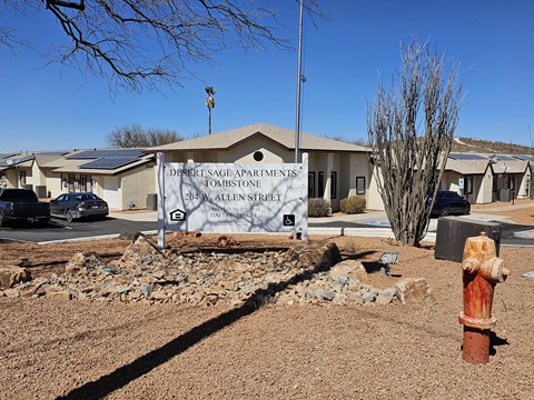 A sign for Desert Sage Apartments in Tombstone, Arizona stands in front of a building.