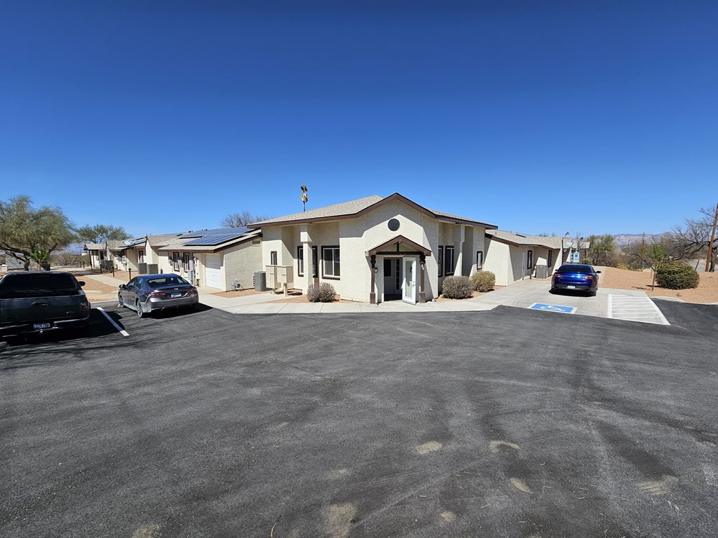 A parking lot in front of a building with cars parked.