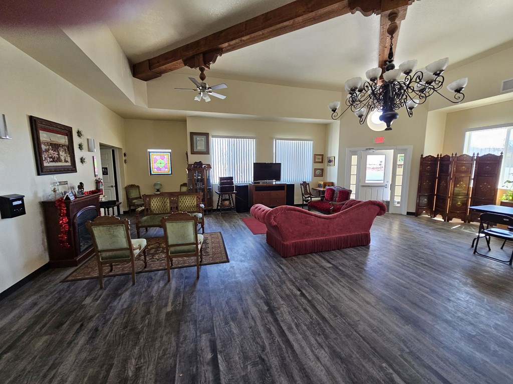 A living room with a red couch and a chandelier.