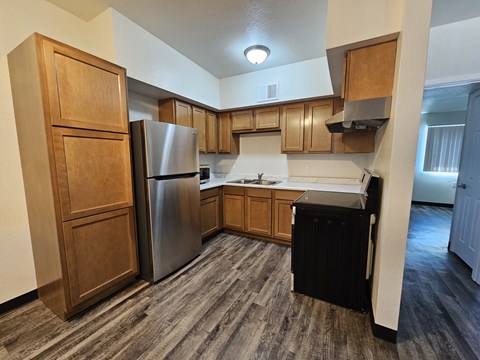 A kitchen with a refrigerator, sink, and cabinets.