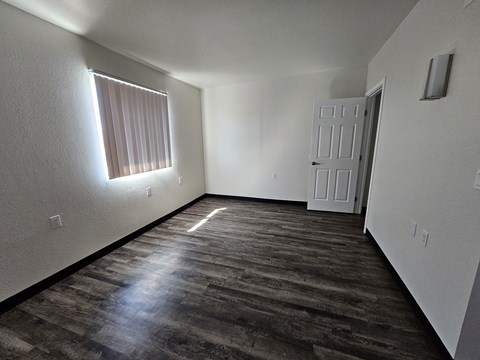 A room with a wooden floor and a window with blinds.