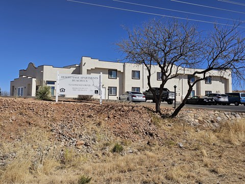 A large building with a sign that says Desert Rose Apartments on it.