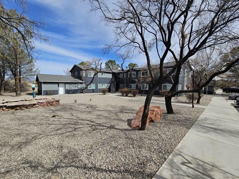 A large grey building with a tree in front of it.