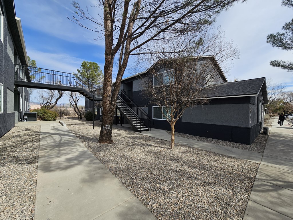 A modern house with a black exterior and a gravel driveway.