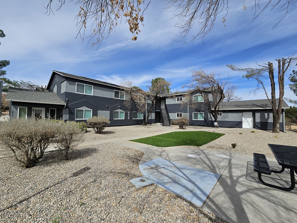 A grey building with a green lawn in front.