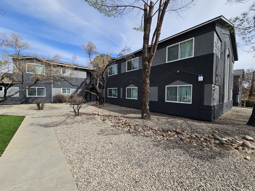A black building with a gravel driveway in front.