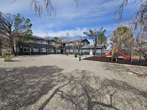 A playground with a slide and a building in the background.