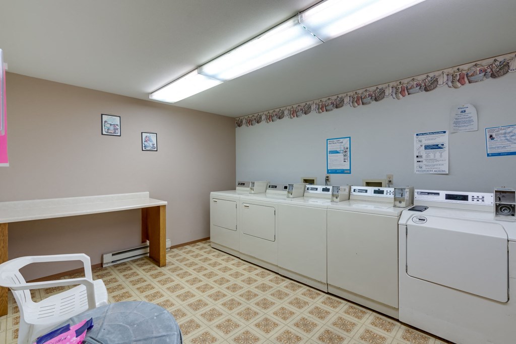 a washer and dryer room with laundry machines and a table