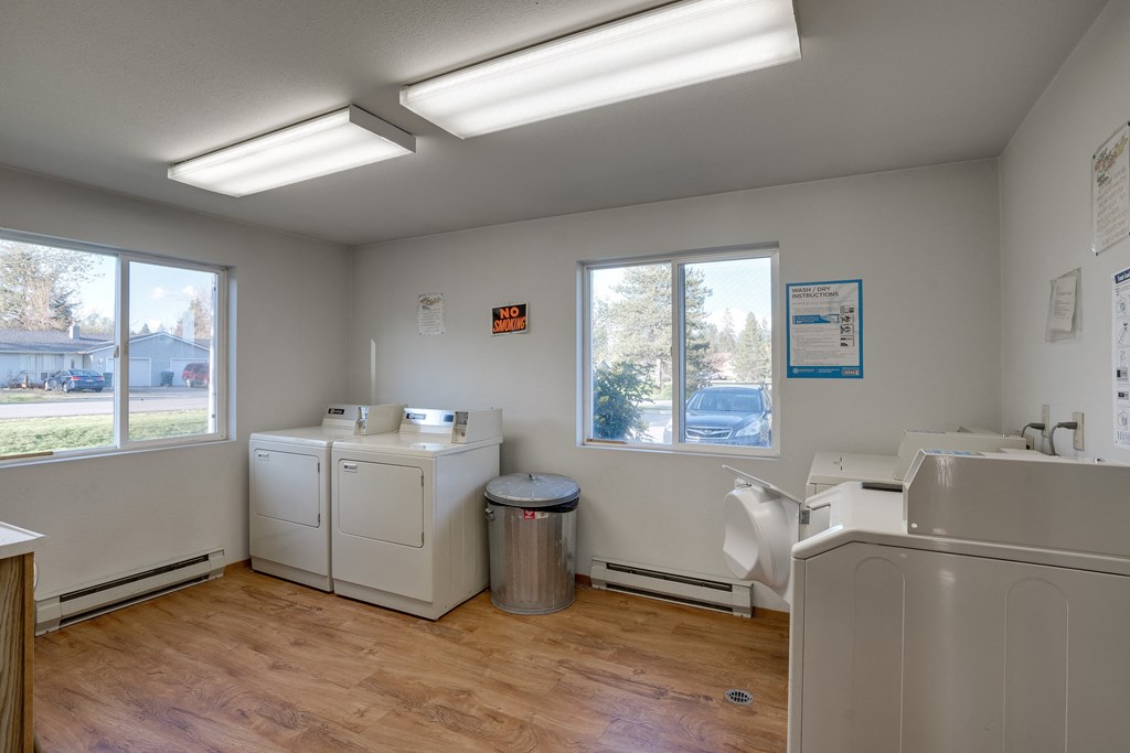 a laundry room with washes and dryers in it and two windows
