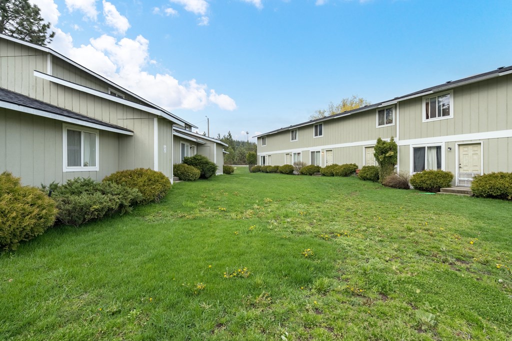a row of houses with a green lawn and a blue sky