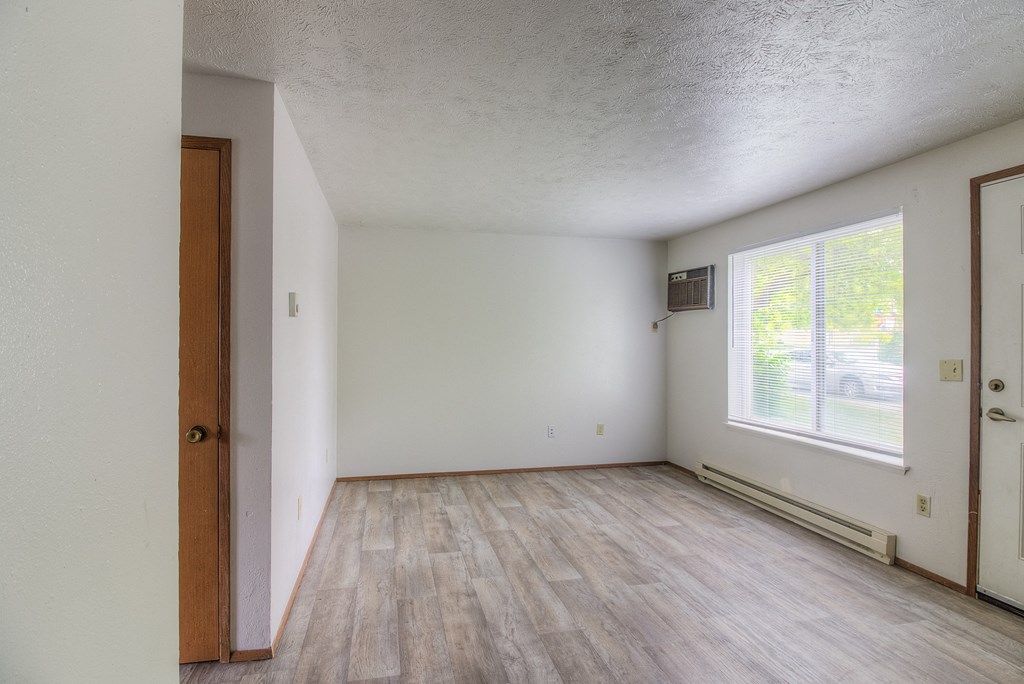 A room with wooden flooring and white walls.