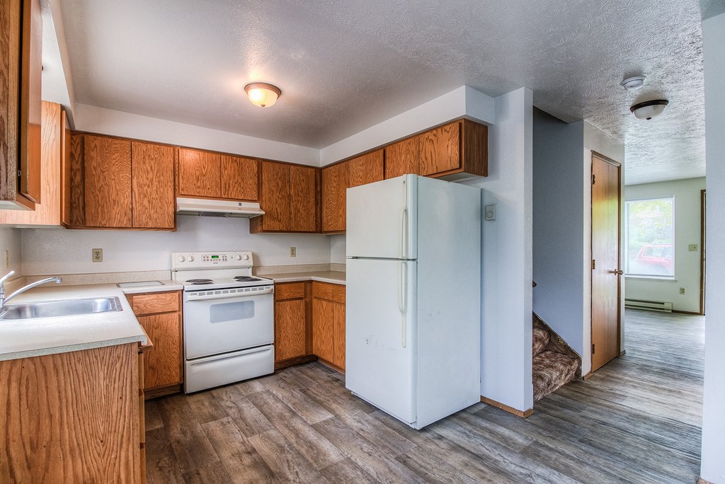 A kitchen with a white fridge and wooden cabinets.