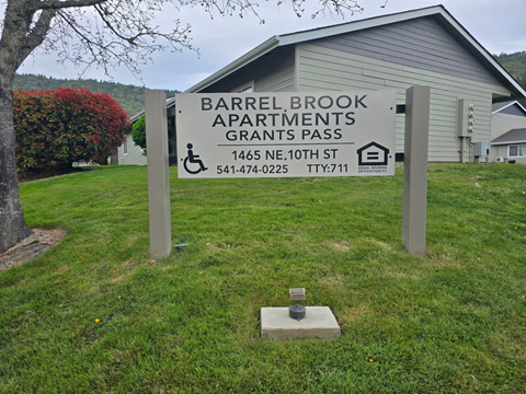 A sign for Barrel Brook Apartments stands in front of a building.