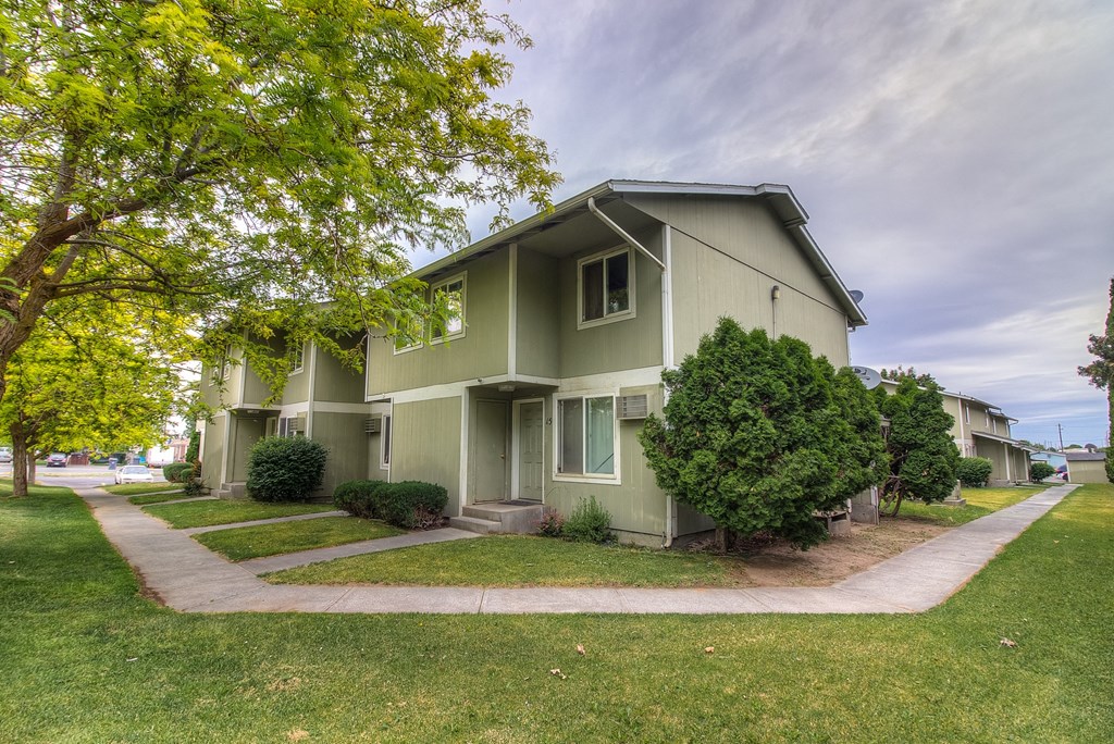 A green house with a tree in front of it.