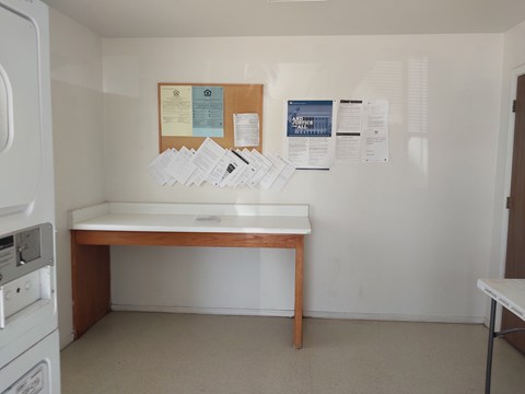 A white wall with a bulletin board and papers on it.