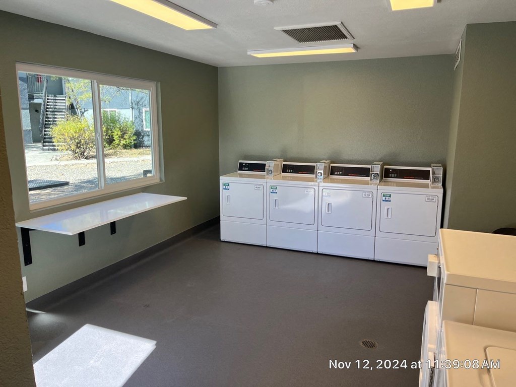 A room with a window, a bench, and a row of white cabinets.