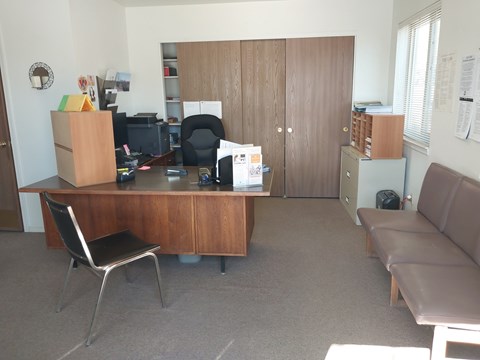 A room with a brown desk, a brown couch, and a brown chair.