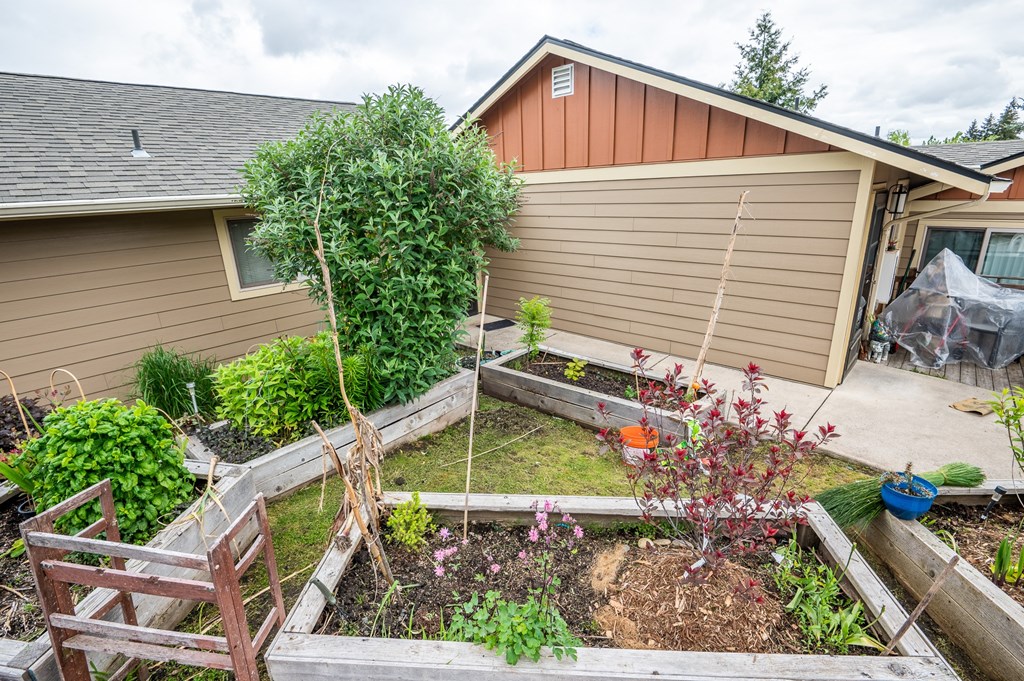 A backyard with a wooden deck and a vegetable garden.
