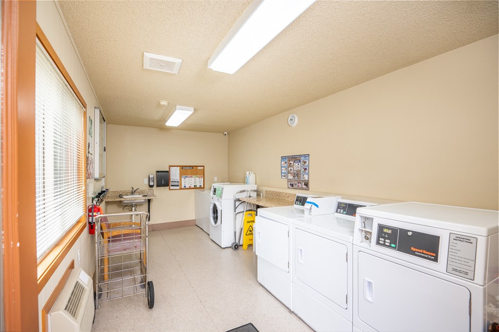 A laundry room with a washer and dryer, a microwave, and a small refrigerator.