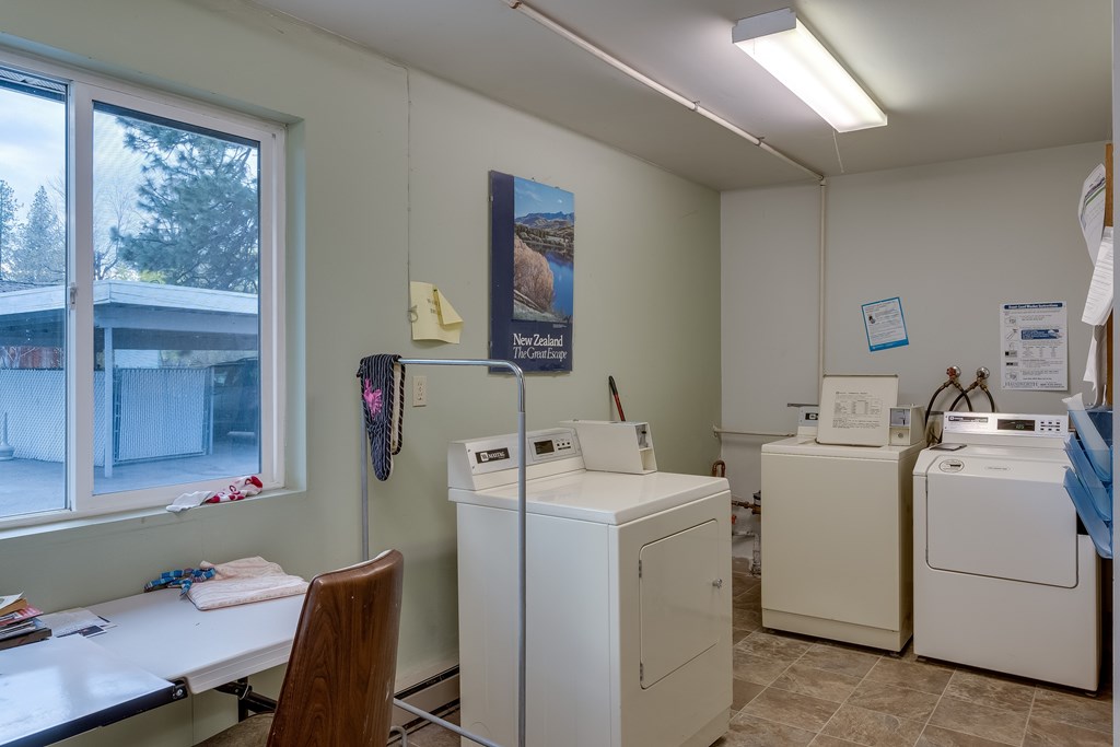 A laundry room with washers and dryers and a window.