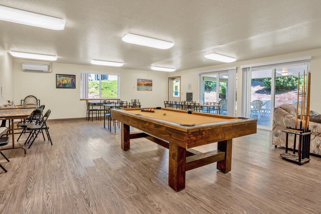 a pool table in a community room with tables and chairs