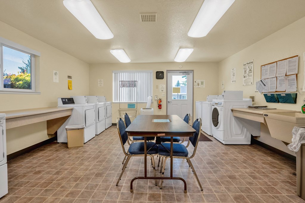 a laundry room with a table and chairs and washing machines