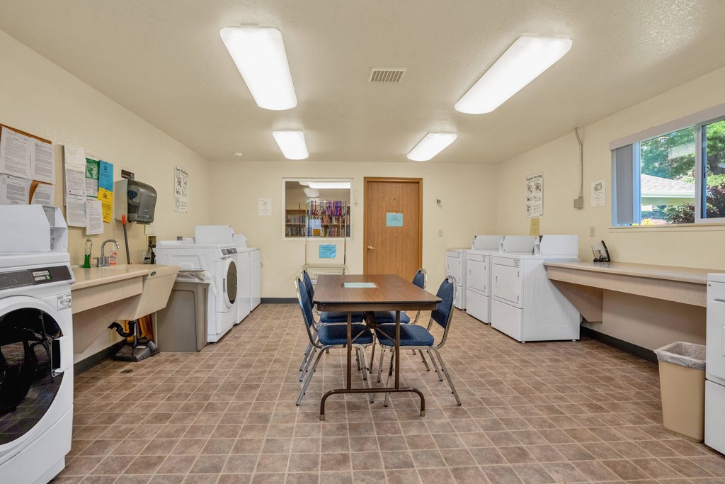 a room with laundry machines and a table and chairs