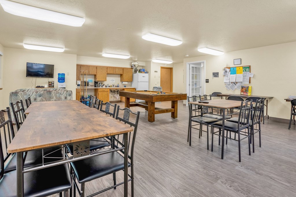 a dining room with tables and chairs and a kitchen