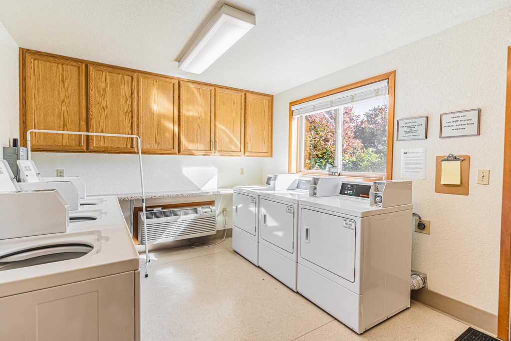 a laundry room with white appliances and wood cabinets