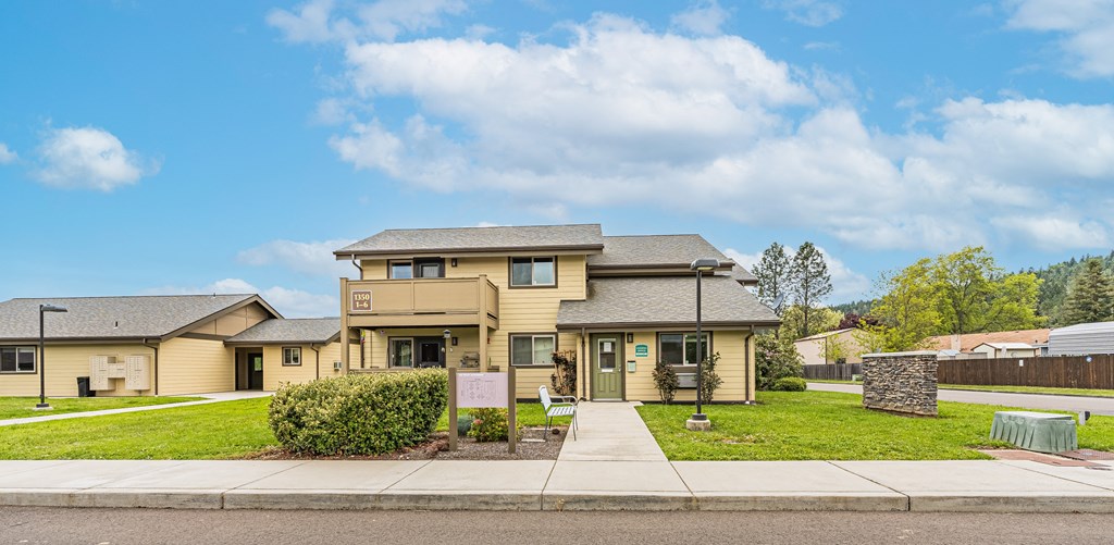 the front of a house with a lawn and a sidewalk