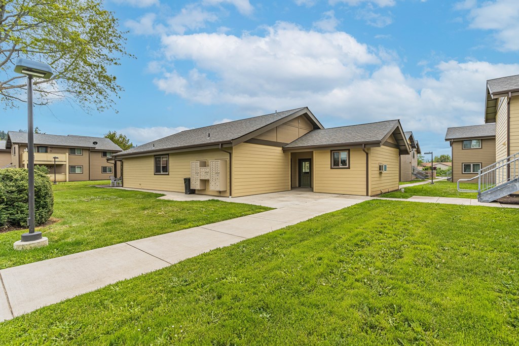 a group of yellow houses with a sidewalk and grass