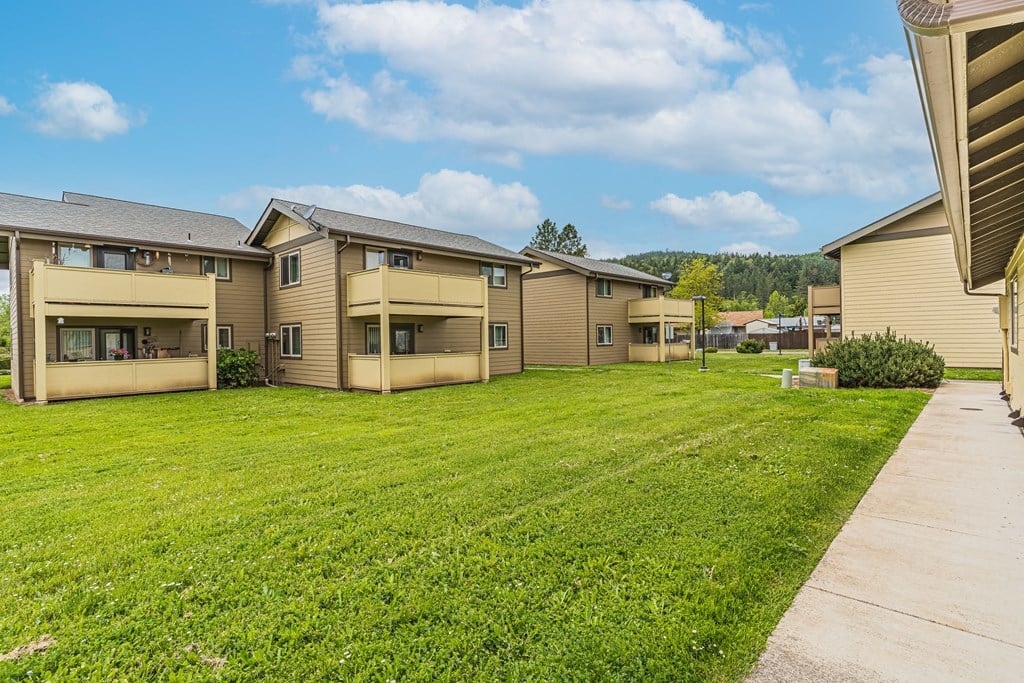 a row of houses with a green lawn and a sidewalk