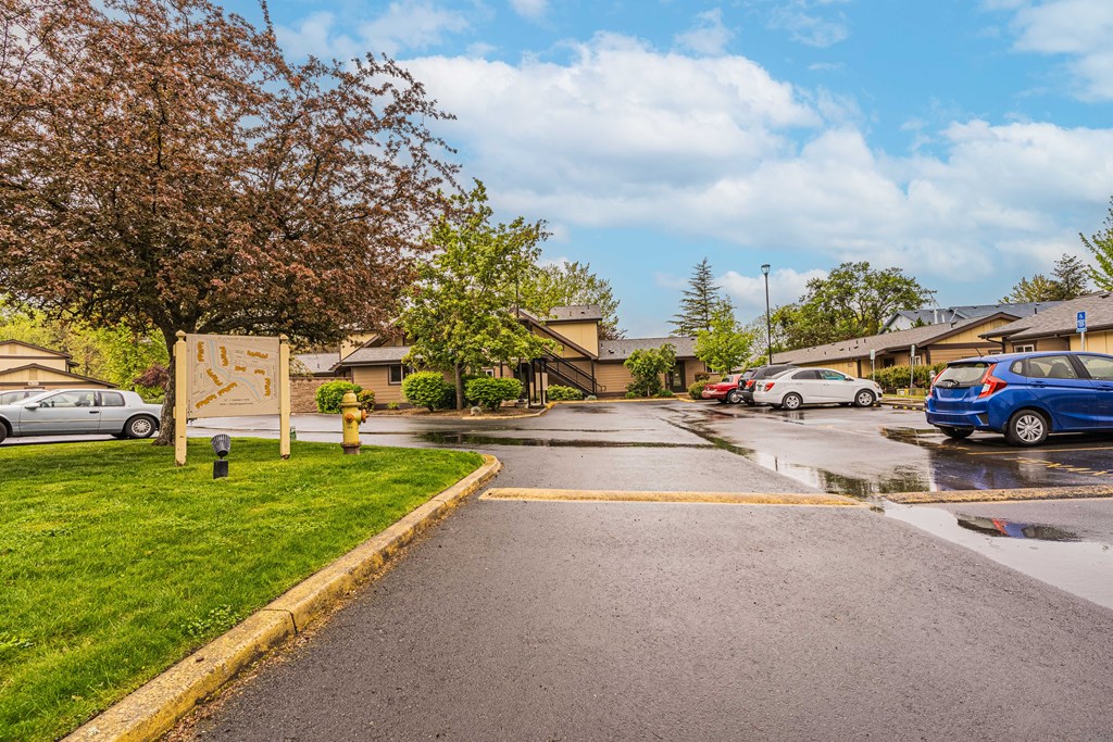 a rainy street in a neighborhood with cars parked on the side of the road