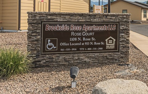 A sign for Brookside Rose Apartments LLC is displayed in front of a building.