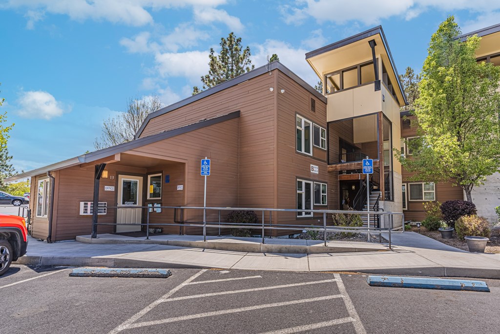 A brown building with a parking lot in front.