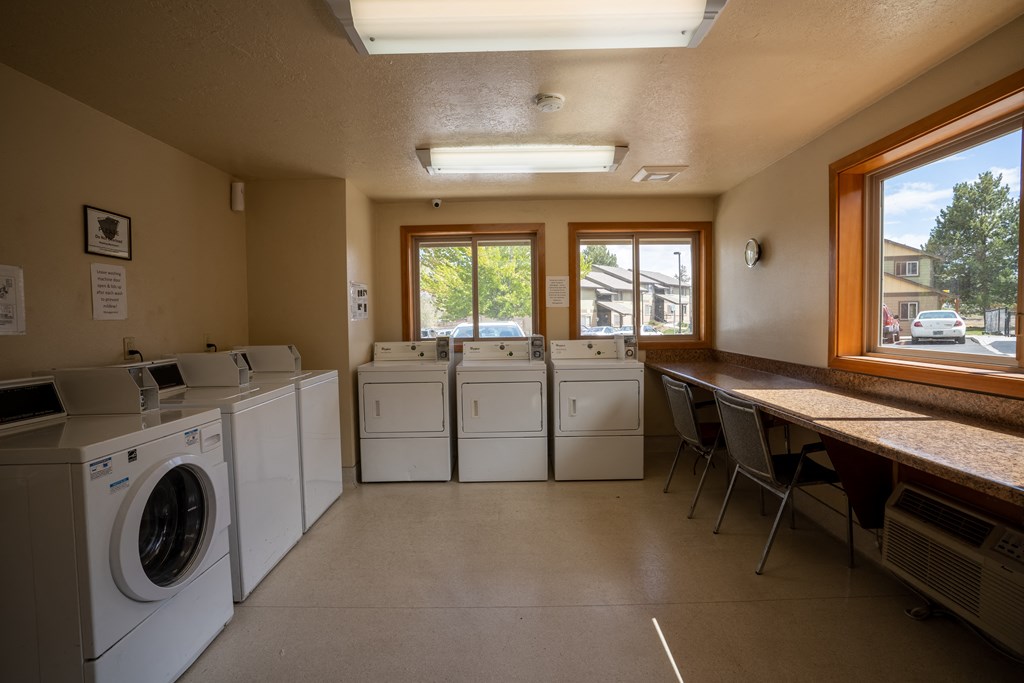 a laundry room with washes and dryers and a table with chairs