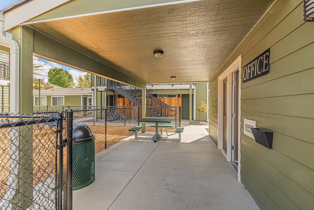a covered patio with a picnic table and a chain link fence