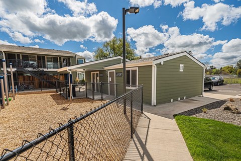 A black fence surrounds a small building and a green shed.