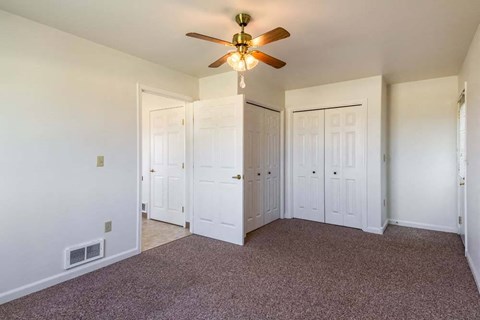 a bedroom with white walls and a ceiling fan