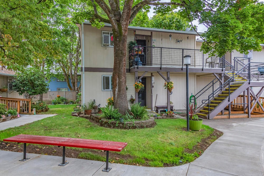 a building with a tree and a red bench in front of it