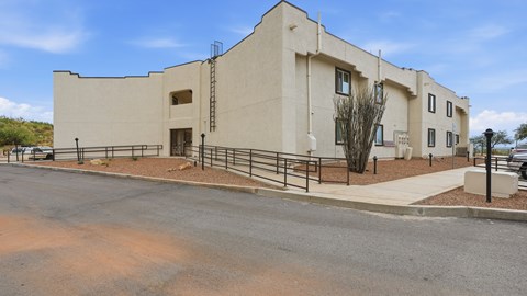 A modern building with a flat roof and a parking lot in front.
