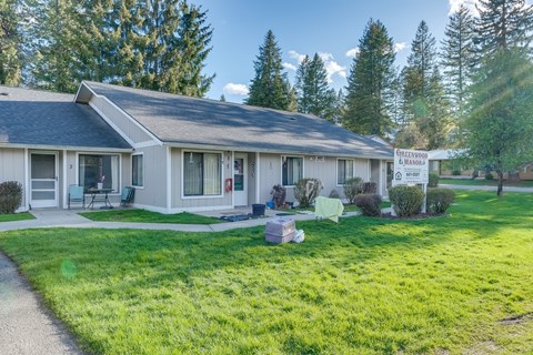 A house with a sign that says "GREENWOOD MANOR" in front of it.